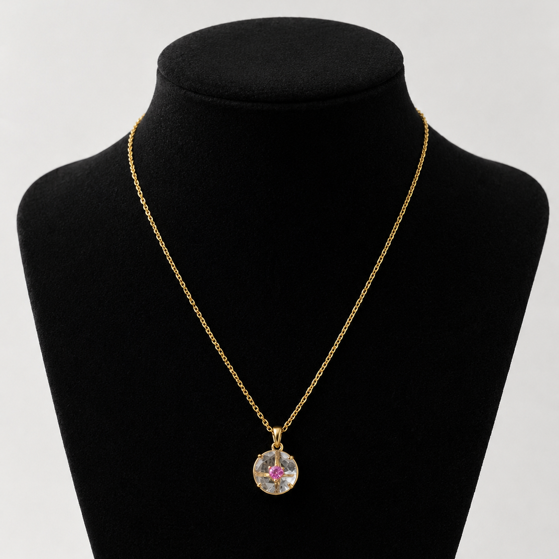 Gold necklace with a pendant on a black mannequin bust against a white background
