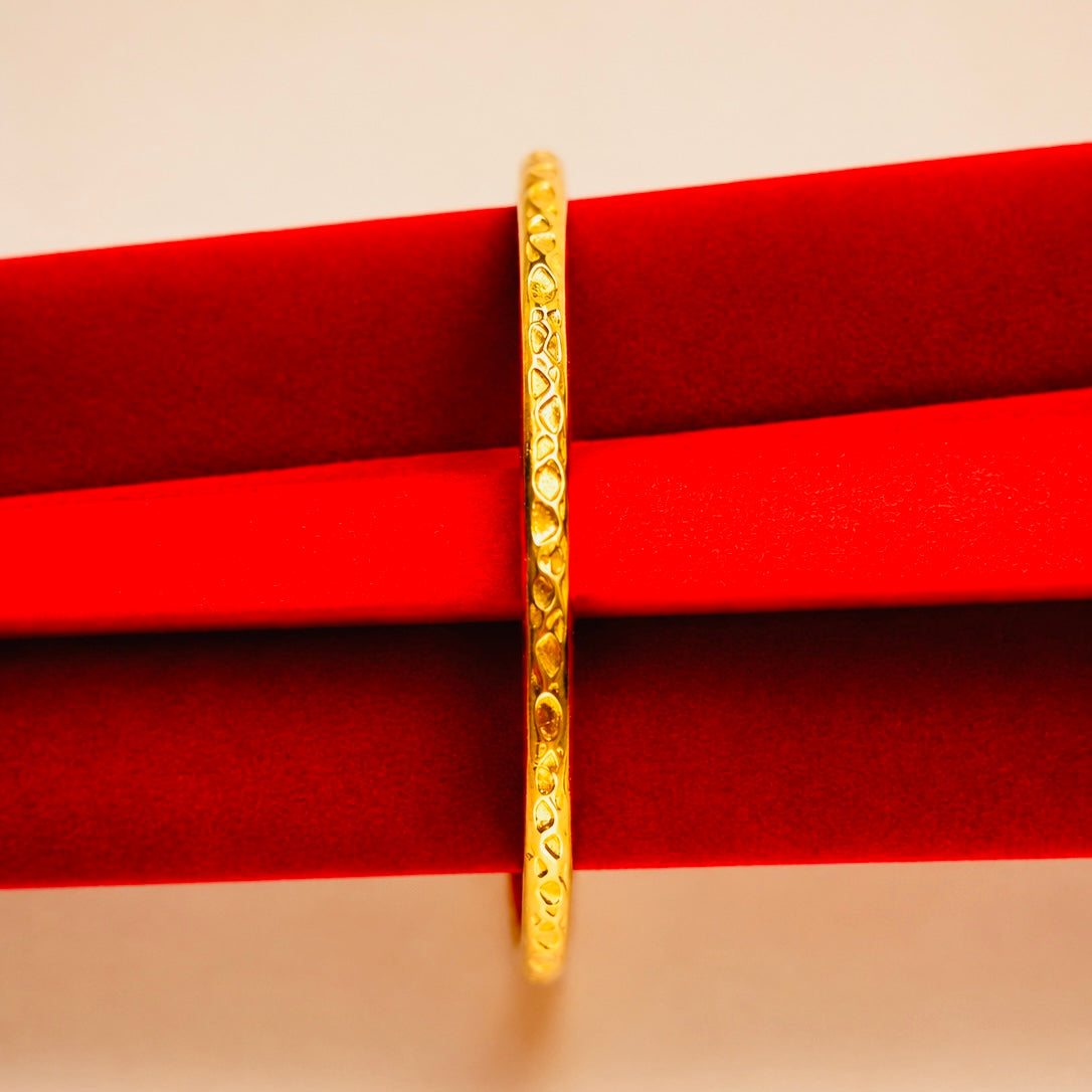 Gold ring with intricate design on a red fabric background