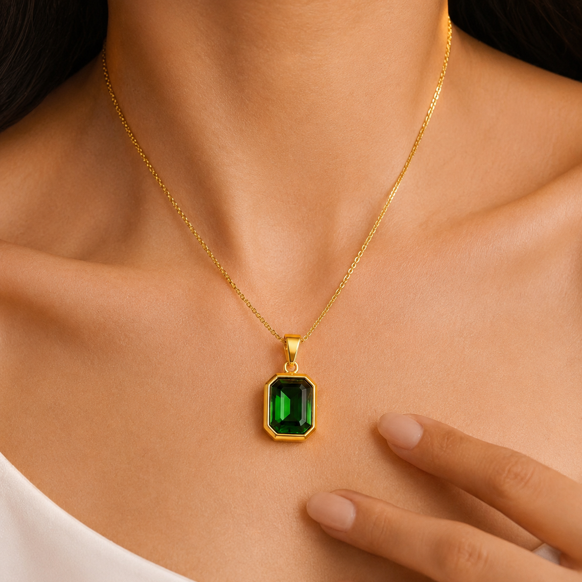 Gold necklace with a green gemstone pendant on a person's neck