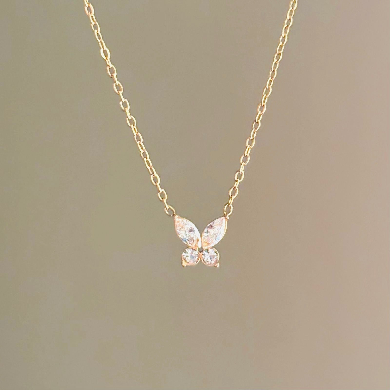 Gold butterfly necklace on a plain background