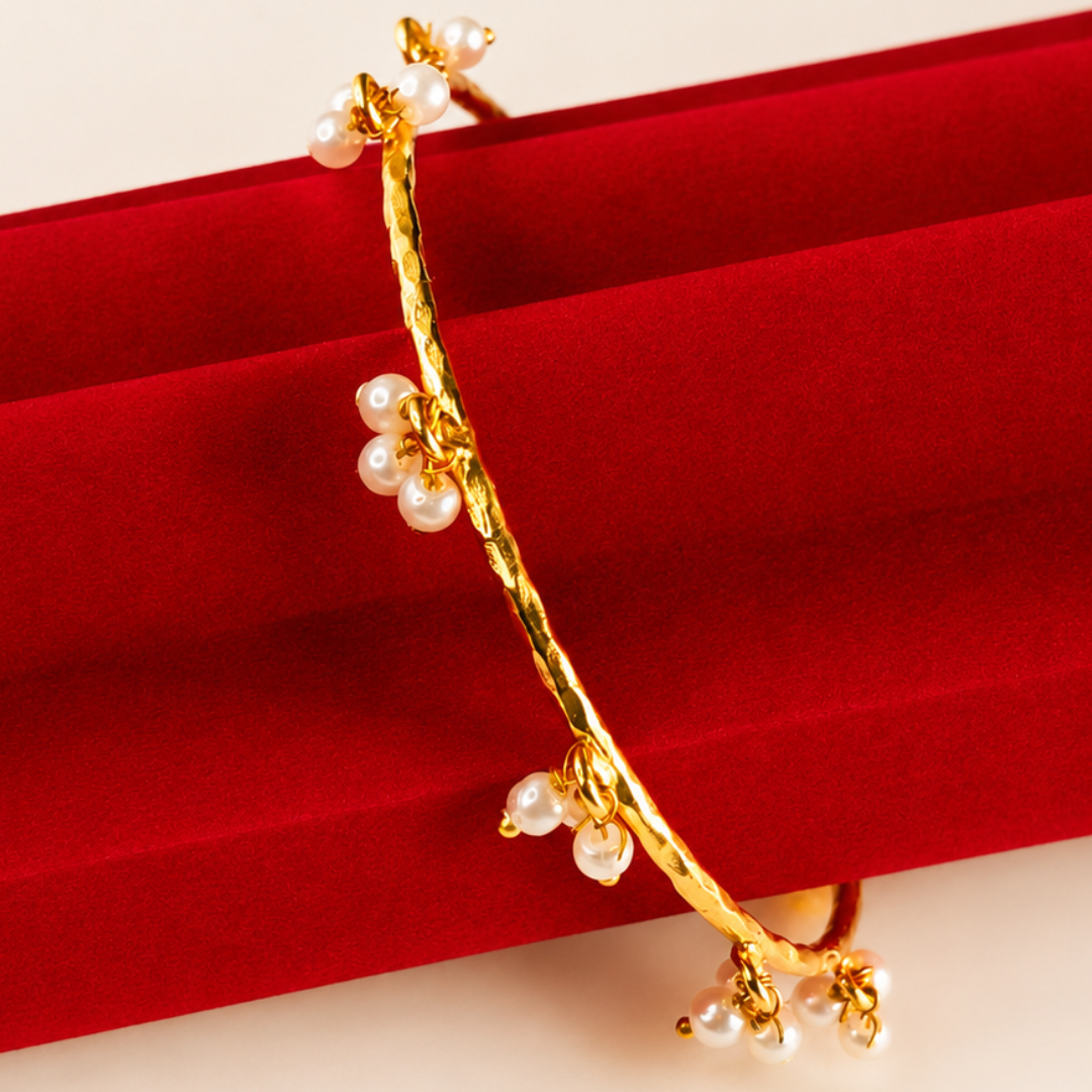 Gold bracelet with pearls on a red velvet background