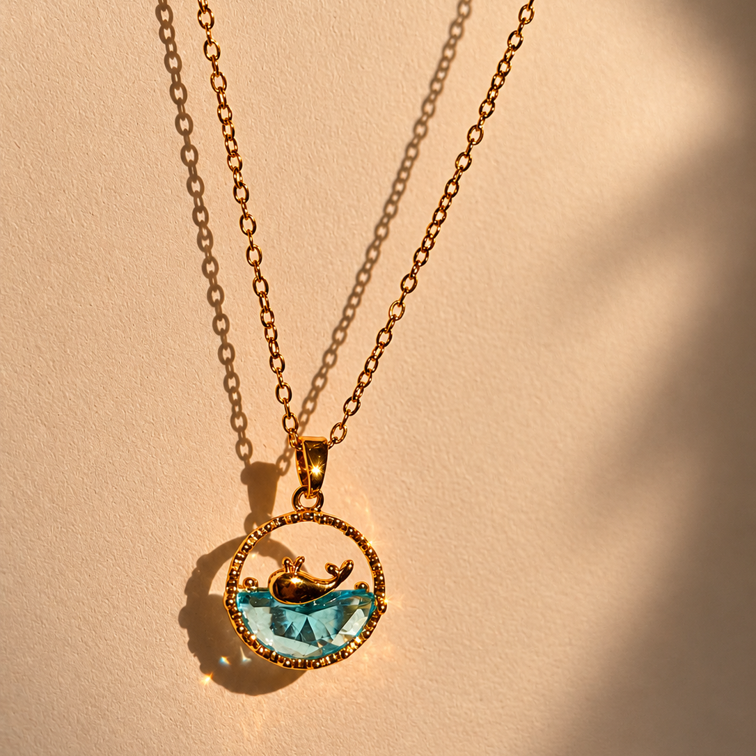 Gold necklace with a pendant featuring a blue gemstone on a beige background