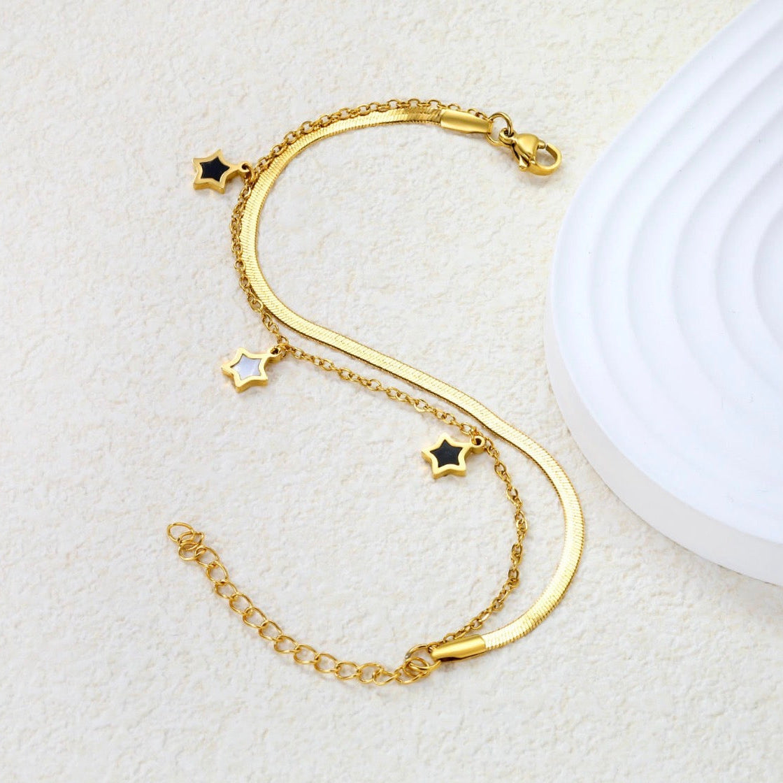 Gold bracelet with star charms on a light gray background