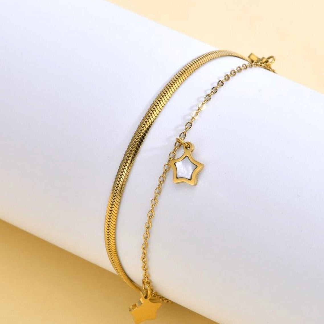 Gold bracelet with star-shaped charm on a white surface