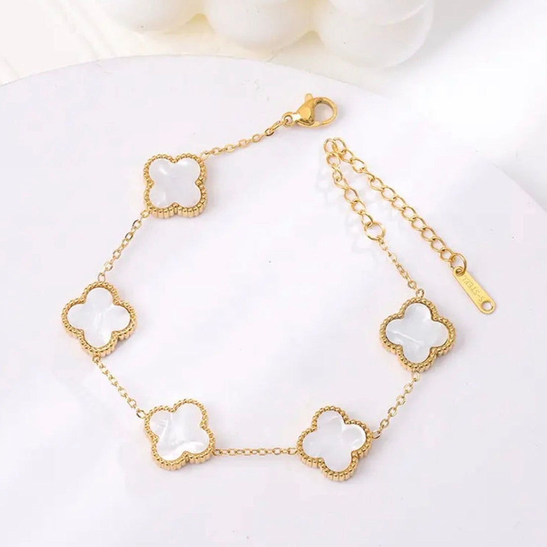 Gold bracelet with clover-shaped links on a white background
