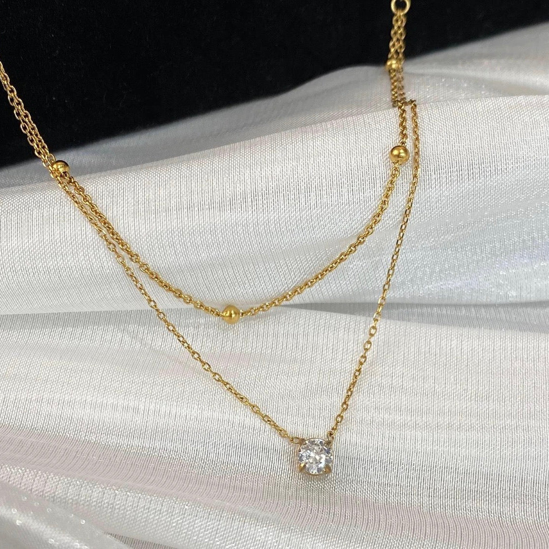 Gold necklace with a diamond pendant on a white fabric background