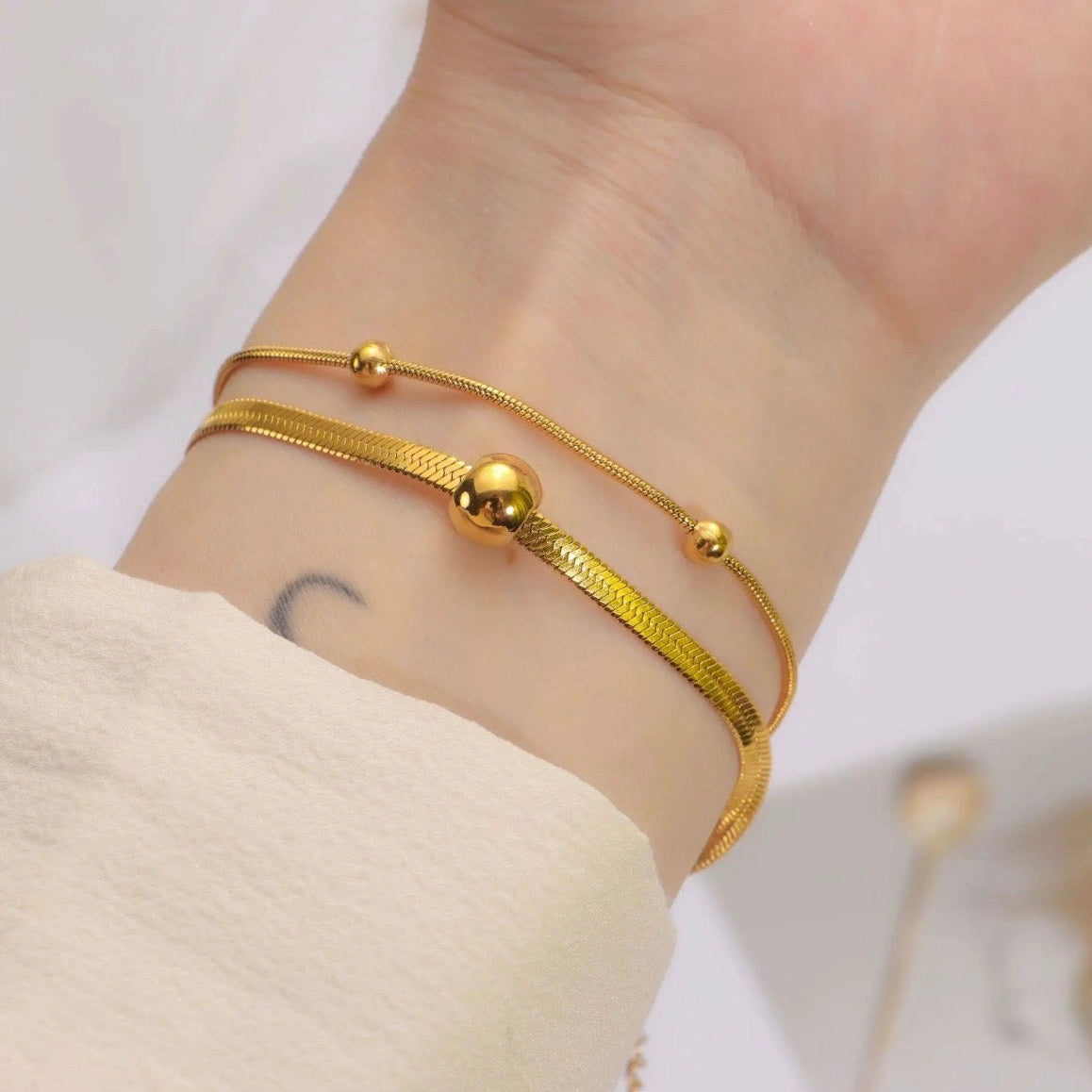 Gold bracelet on a wrist with a plain background