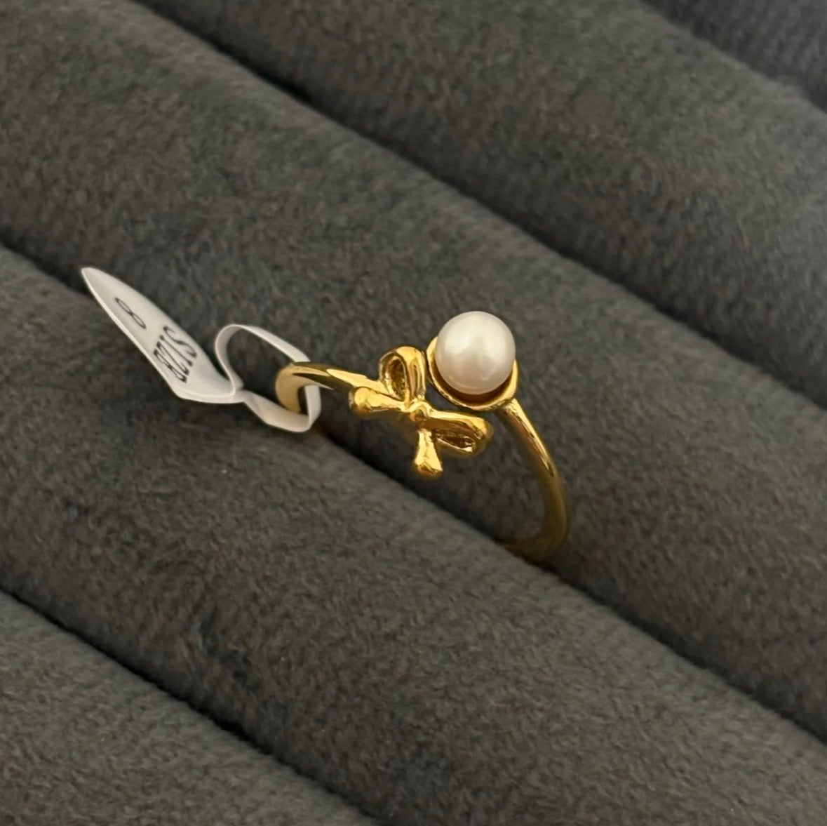 Gold ring with a pearl on a gray textured surface