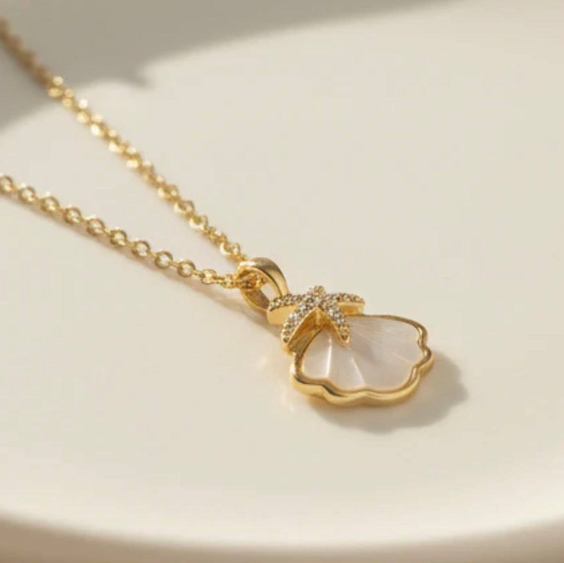 Gold necklace with a heart-shaped pendant on a light background