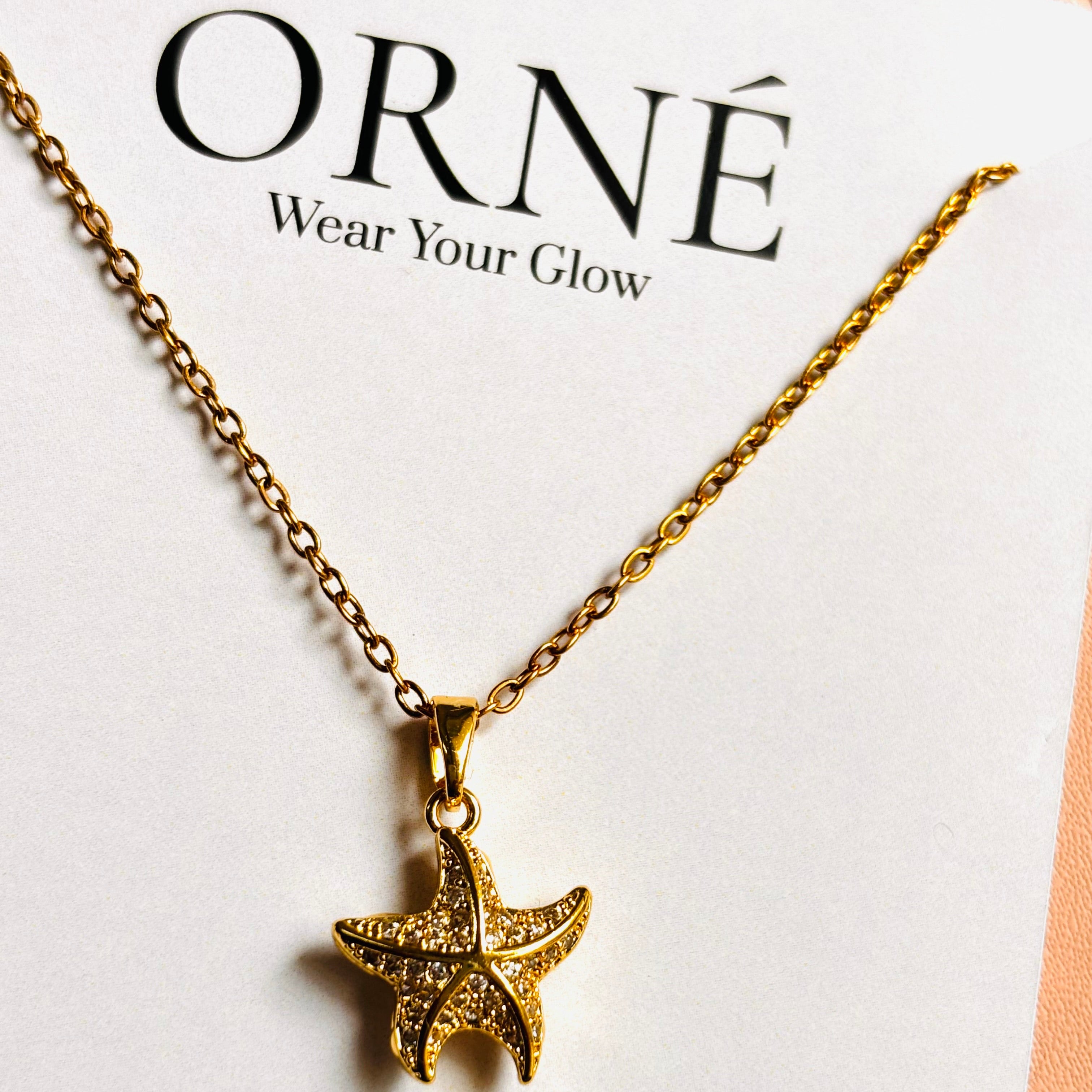 Gold star-shaped pendant necklace on a white card with 'ORNé' branding.