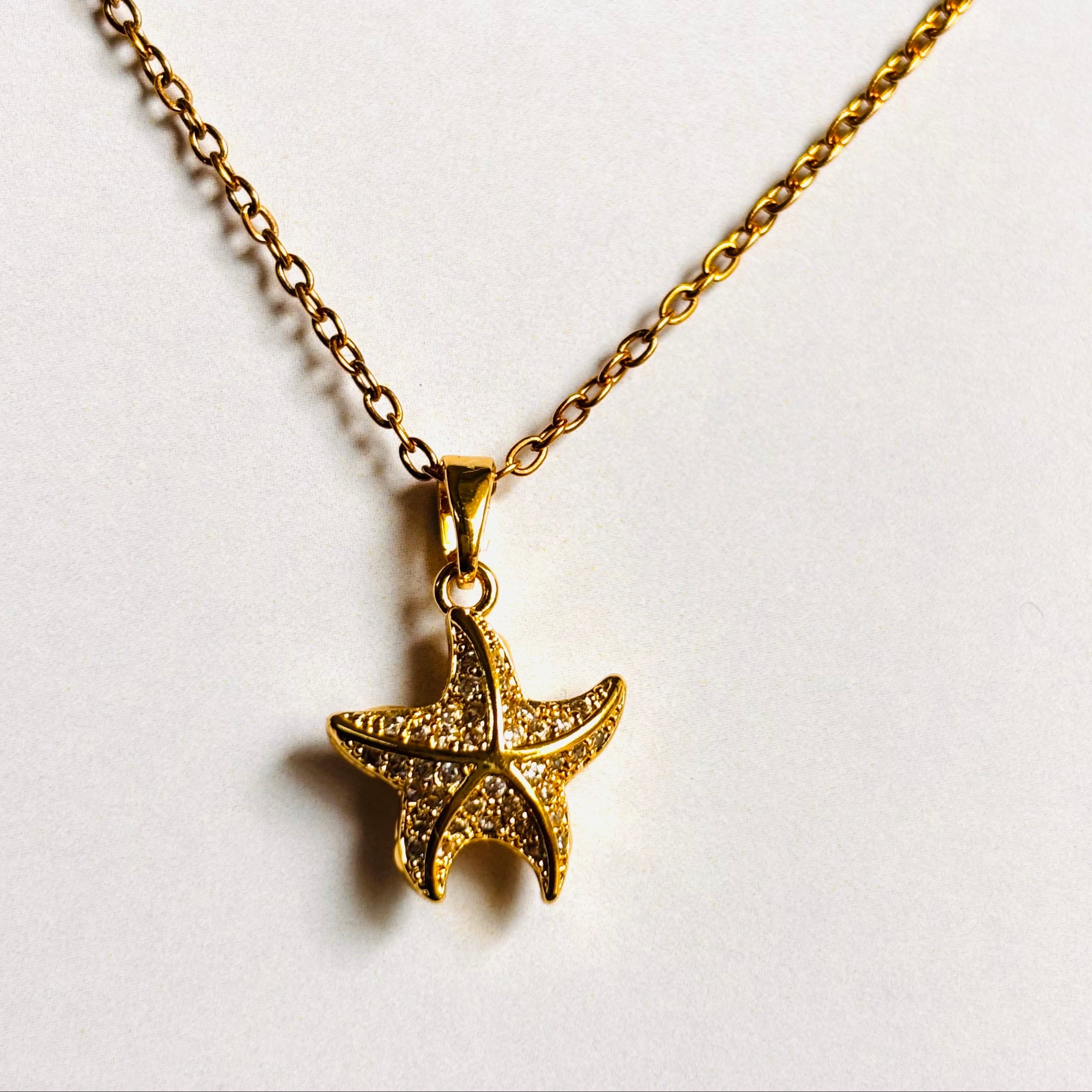Gold starfish pendant necklace on a white background