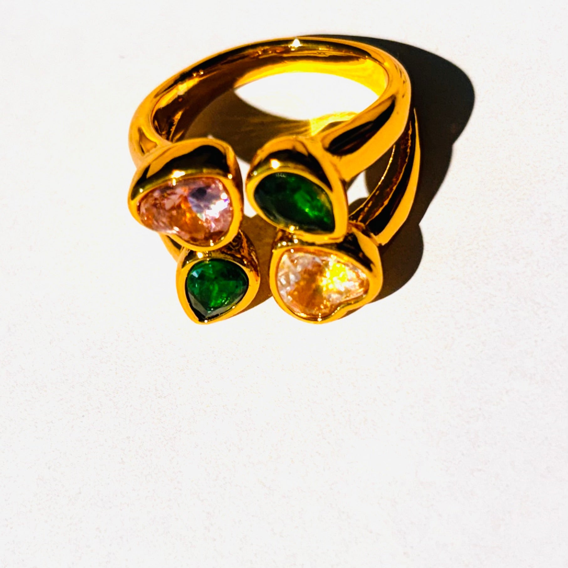 Gold ring with green and orange gemstones on a white background
