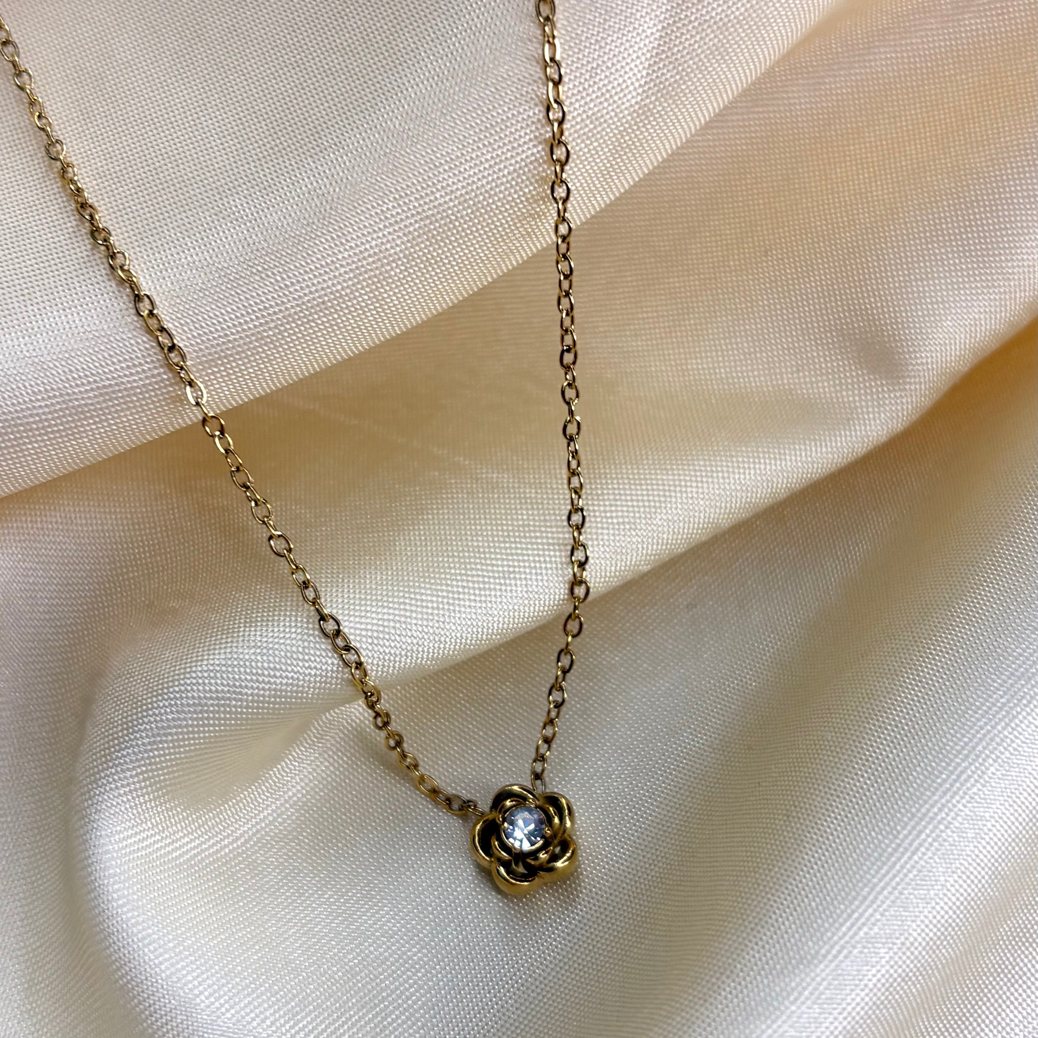 Gold necklace with a floral pendant on a beige fabric background
