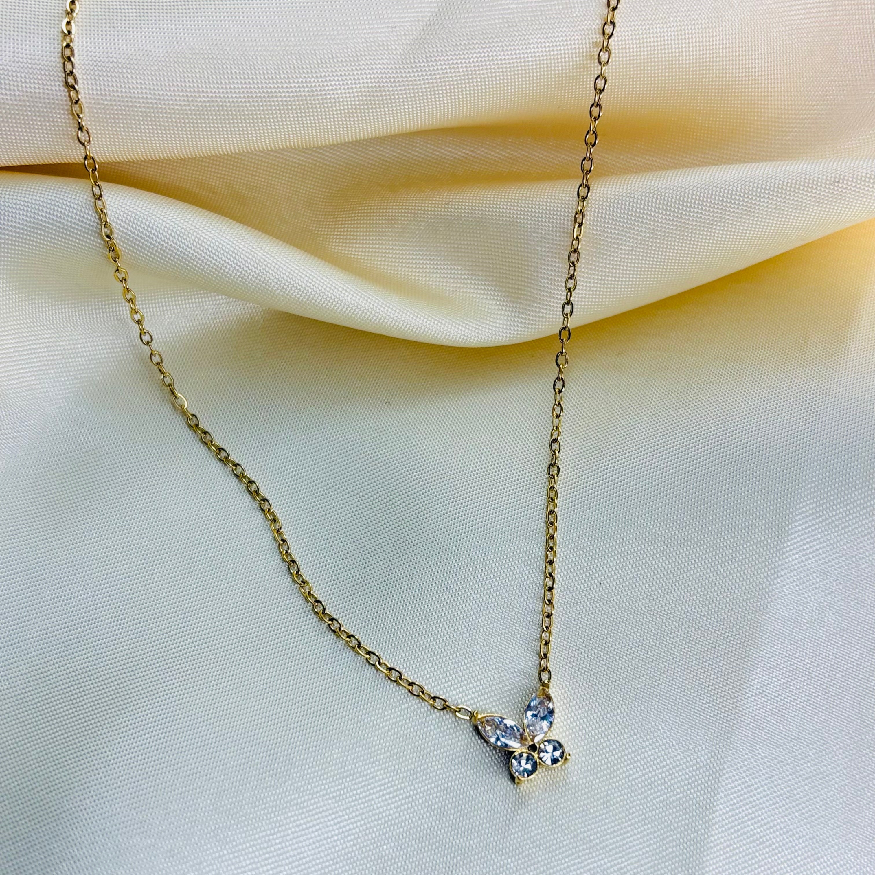 Gold necklace with a small pendant on a beige fabric background