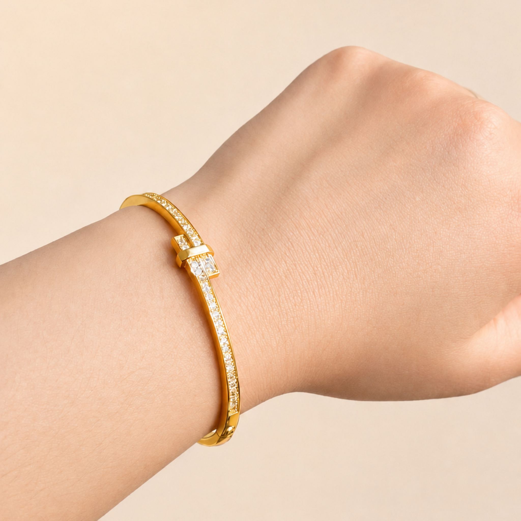 Gold bracelet with diamonds on a wrist against a beige background