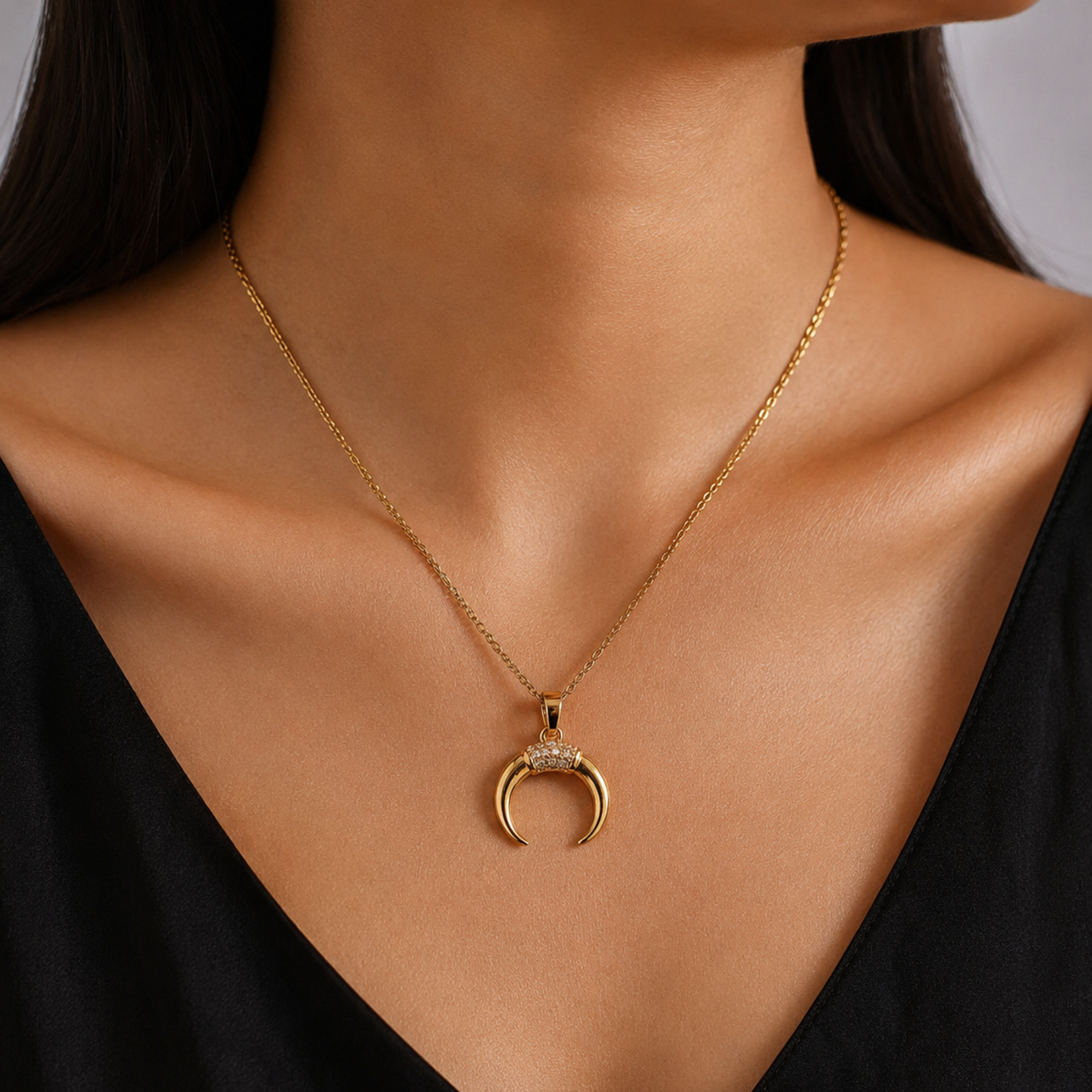 Gold necklace with a crescent moon pendant on a model wearing a black top.