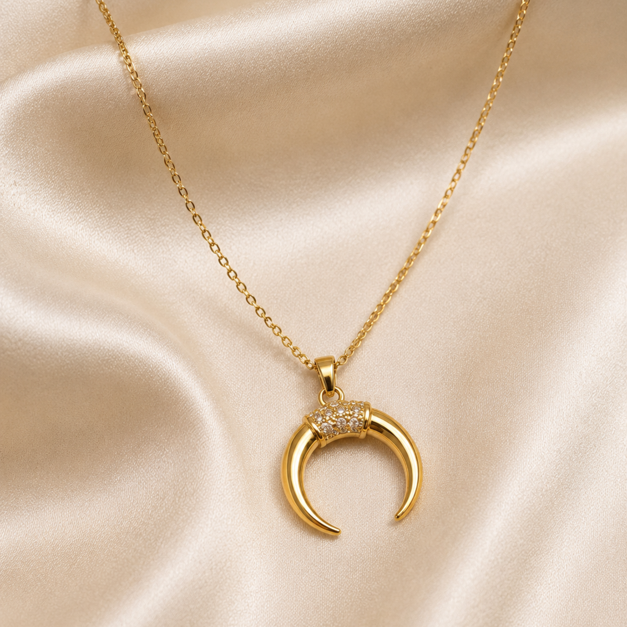 Gold necklace with a crescent moon pendant on a beige fabric background