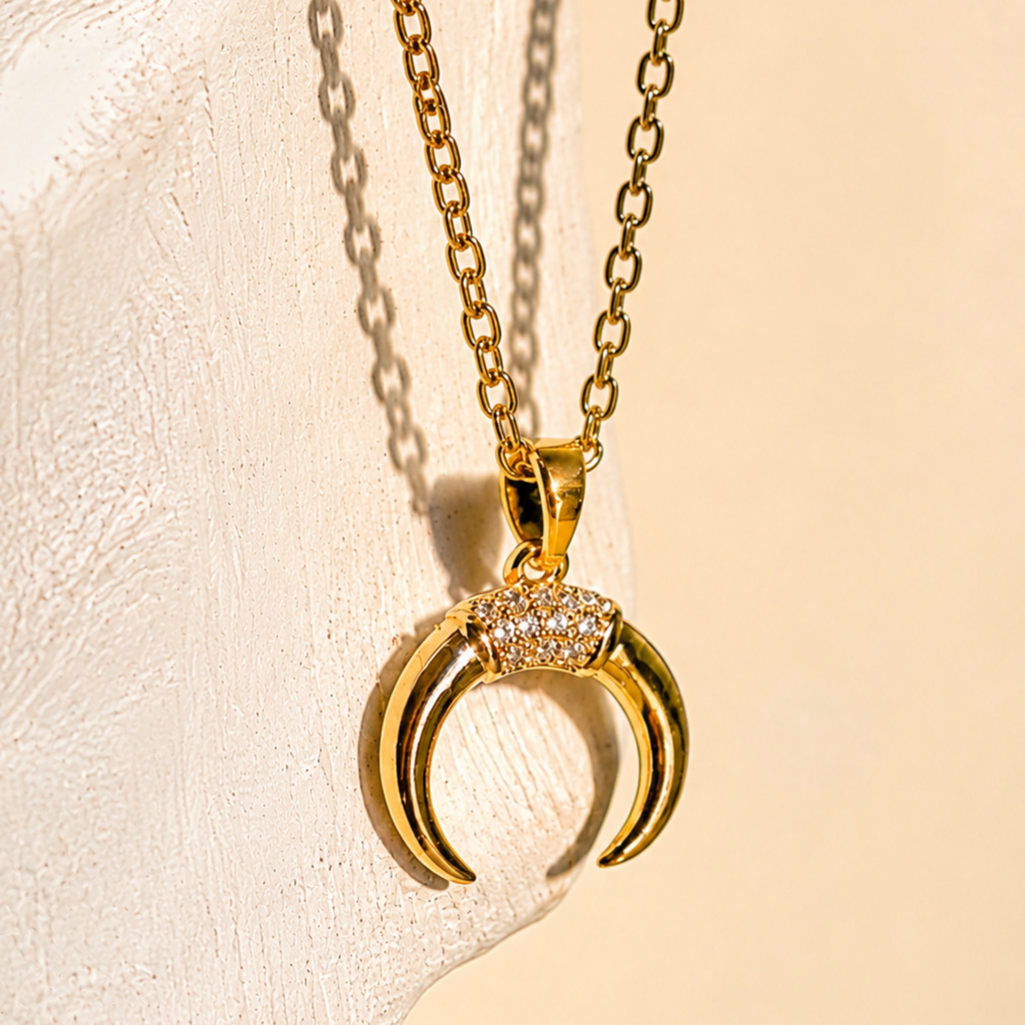 Gold necklace with a crescent moon pendant on a beige background