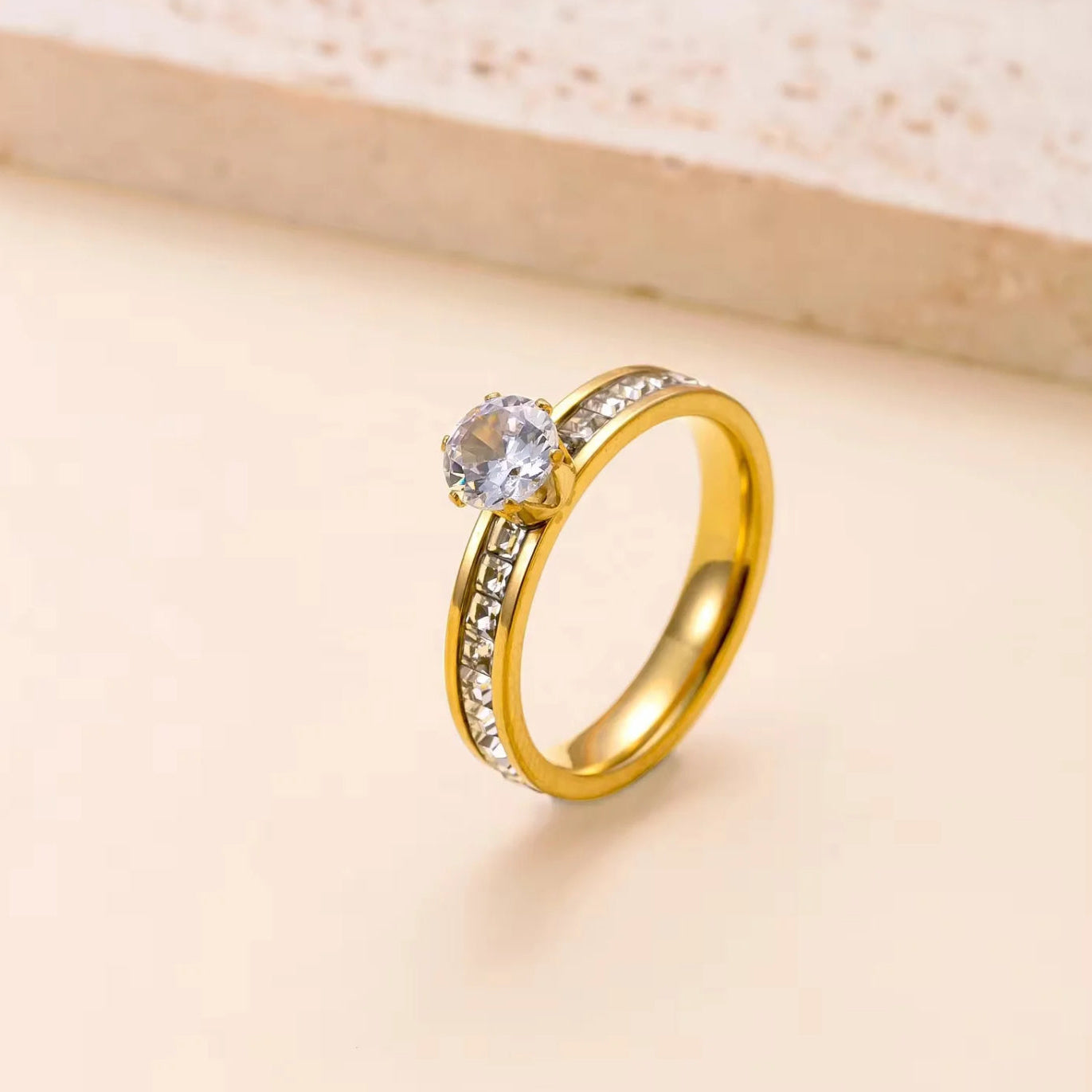 Gold ring with a diamond on a beige background
