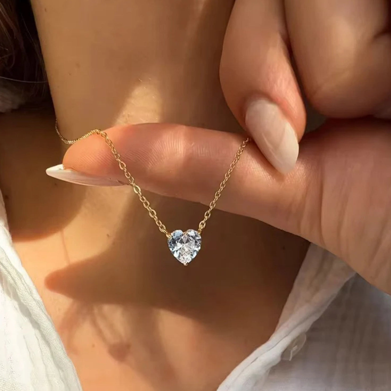 Heart-shaped diamond necklace held by a hand