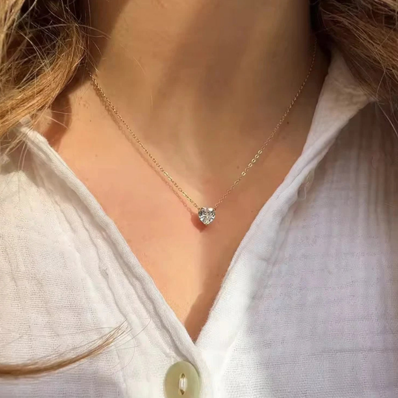 Necklace with a diamond pendant worn by a person in a light-colored shirt.