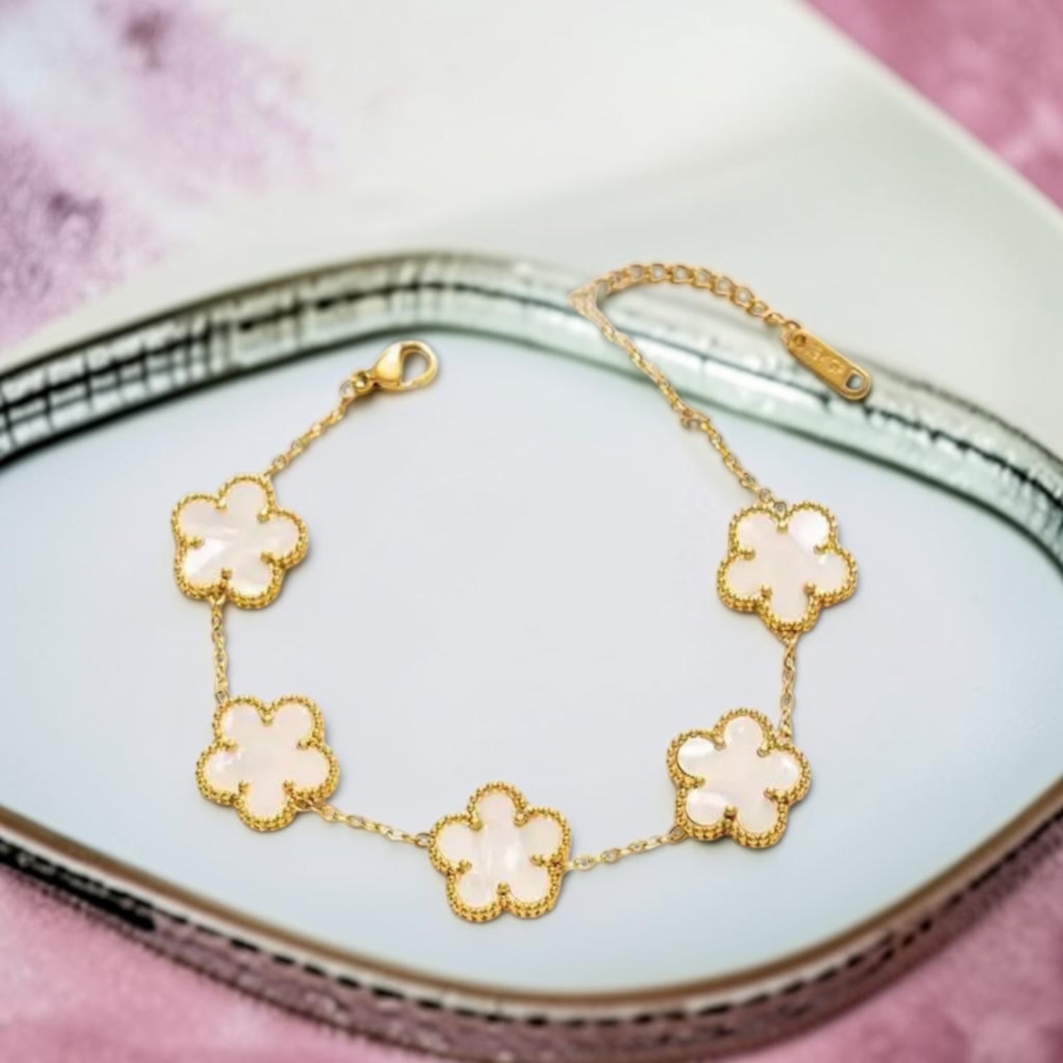Gold bracelet with clover-shaped charms on a decorative plate