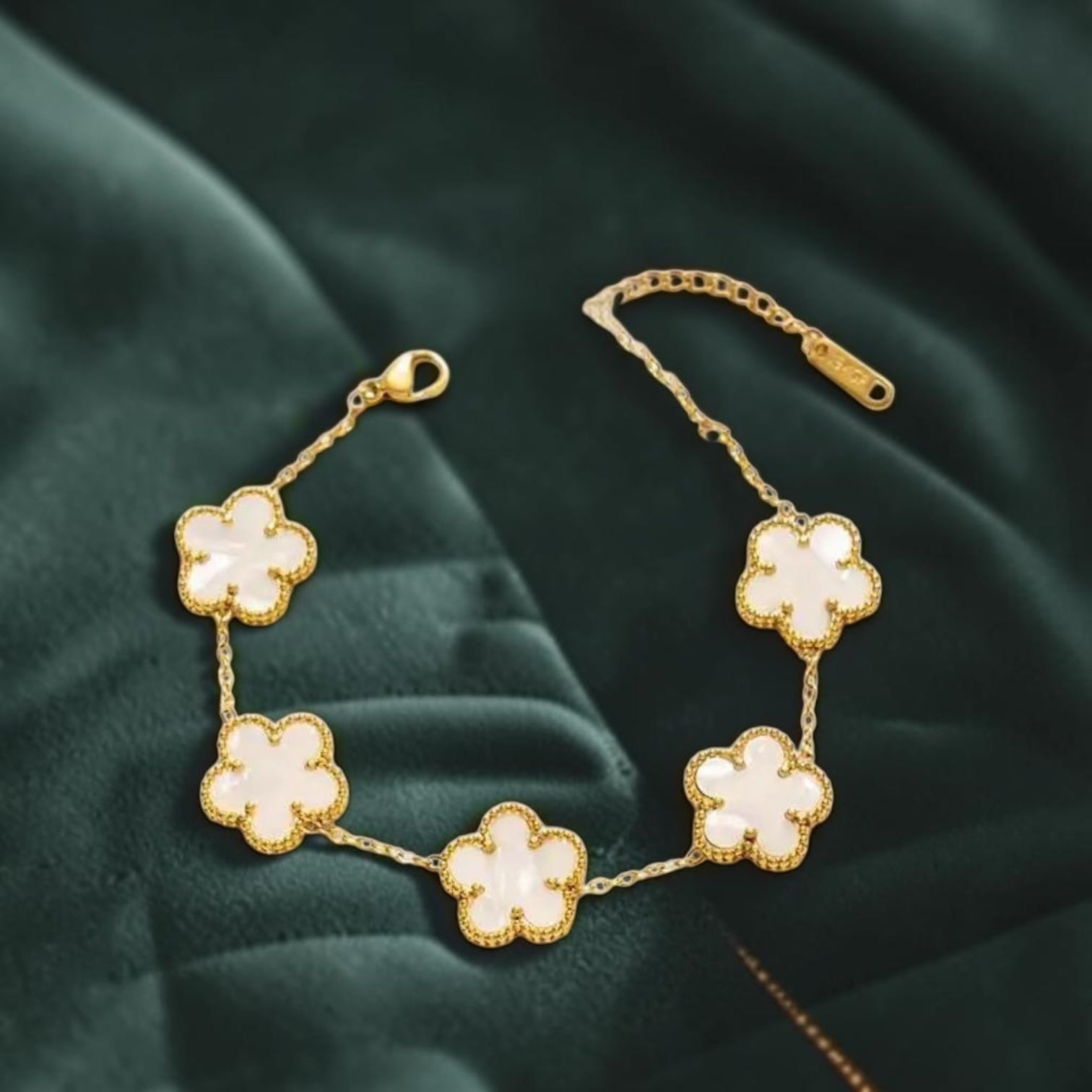 Gold floral bracelet on a dark green fabric background